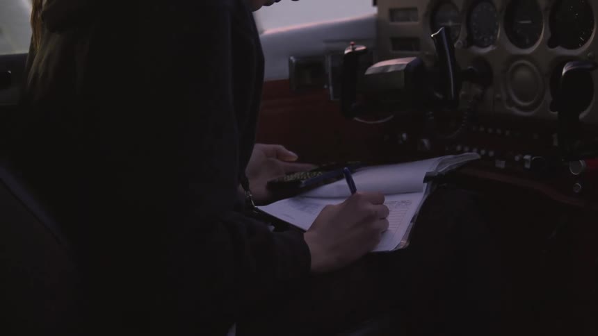 Woman writing notes in the cockpit of a small airplane