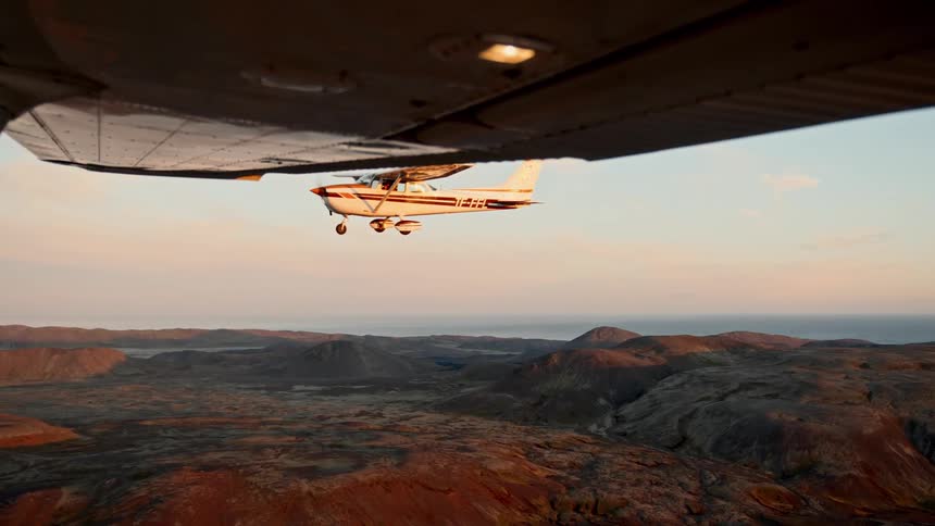Two airplanes flying side by side over the mountains at sunset