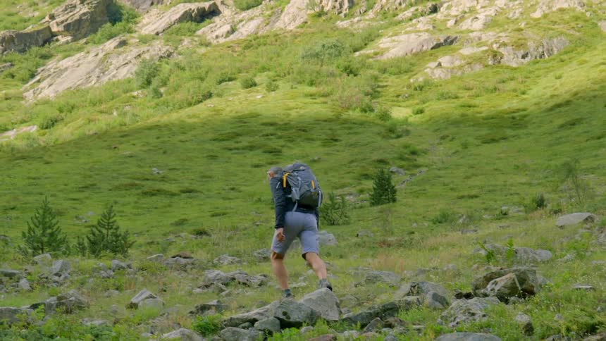Man hikes over a rocky mountainous landscape