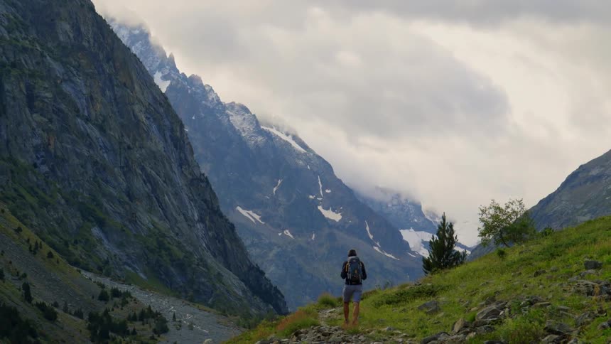 Man backpacking on a trail in the mountains on a cloudy day