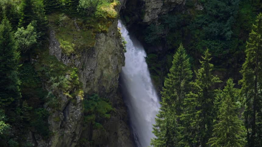 Large waterfall plunging over rock cliffs in forest wilderness