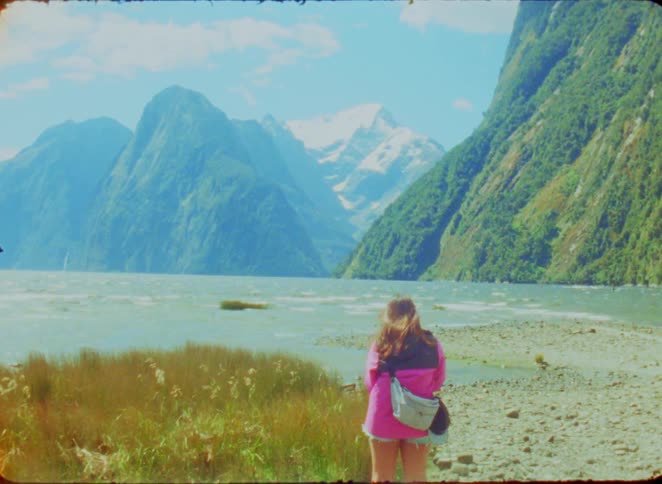Woman facing the sea surrounded by mountains