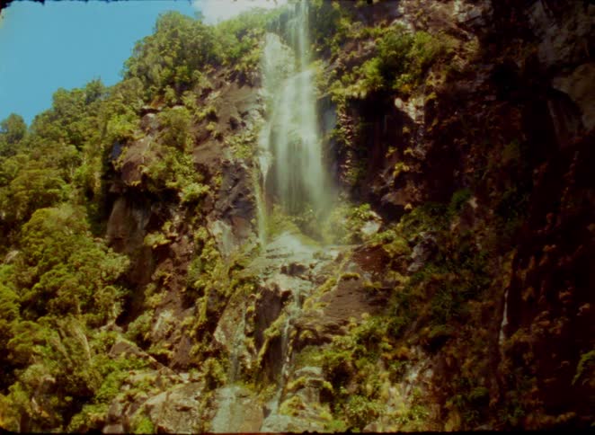Waterfall flowing down a rocky cliff surrounded by vegetation