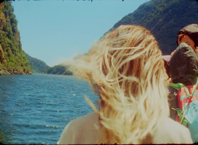 Crew members on a boat enjoying the natural scenery of the sea surrounded by mountains