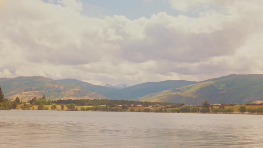 Lake with hills and mountains under a cloudy sky