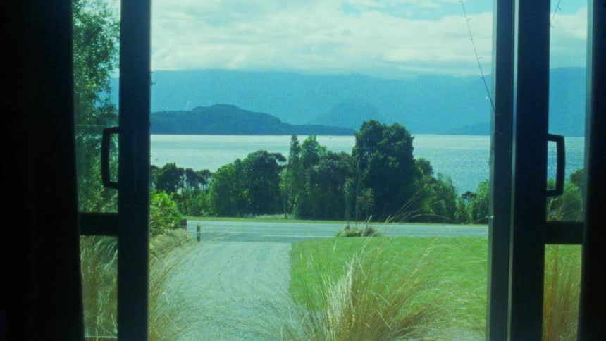 Motorhome passing by the roadside with a lake and mountains in the background visible through a window