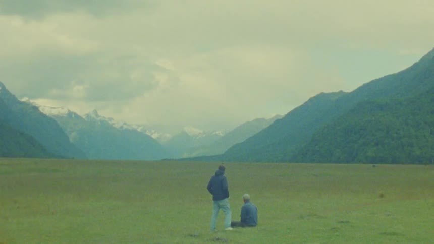 Two men sitting outdoors on a grassy field