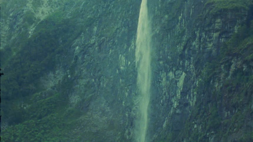 A tall waterfall cascading down a lush green mountainside