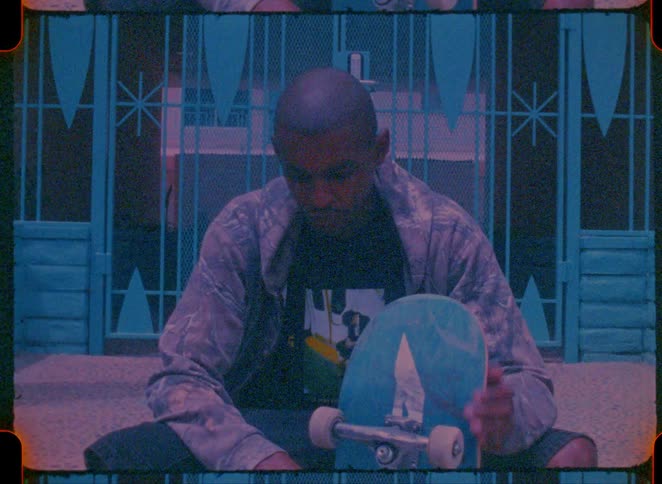 A man sitting outdoors with a skateboard