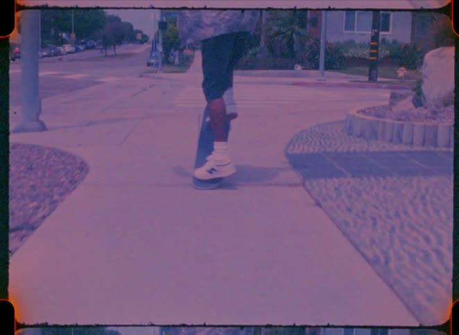 Man skateboards through an urban intersection with a green traffic light