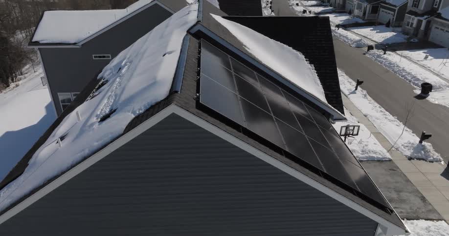 Snow melts off solar panels on a house roof in winter
