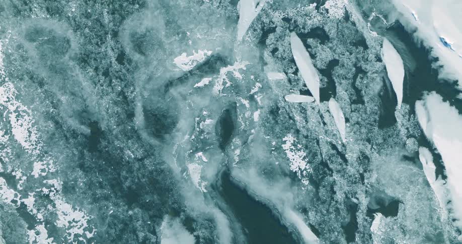 Fragmented ice formations float over dark water seen from above