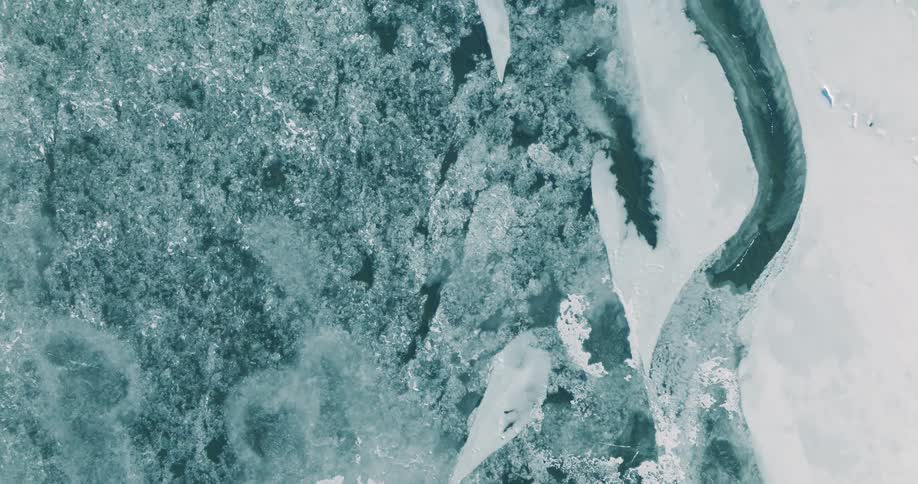 Fragmented ice blocks float over dark water seen from above