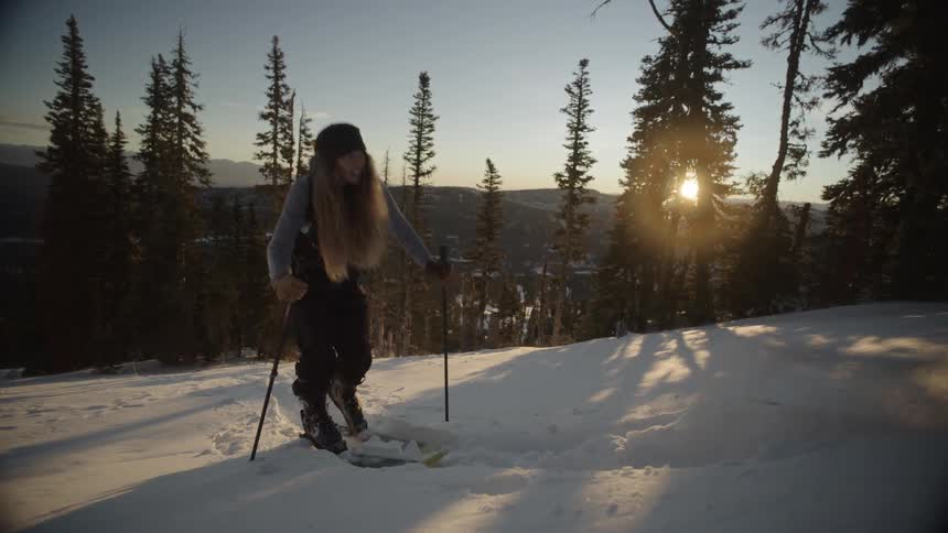 A woman on skis walking up a mountain