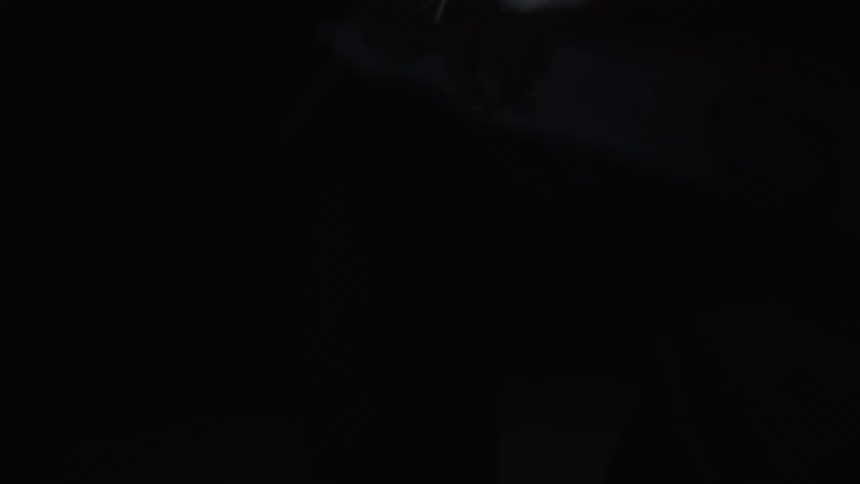 A young man wearing a headlamp picking up a snowboard outdoors at night