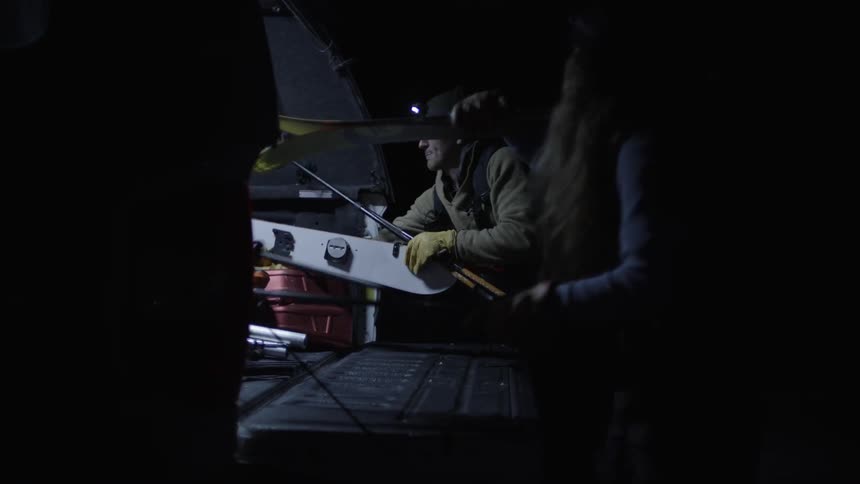 Two people retrieving ski equipment from a car