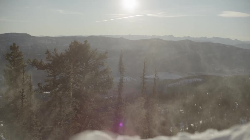 View of mountains with trees and the sun shining in the sky