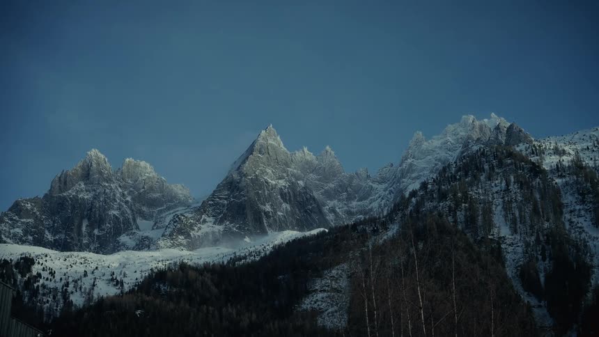 Snow and ice covered the rough terrain of mountains with peaks high in a blue sky