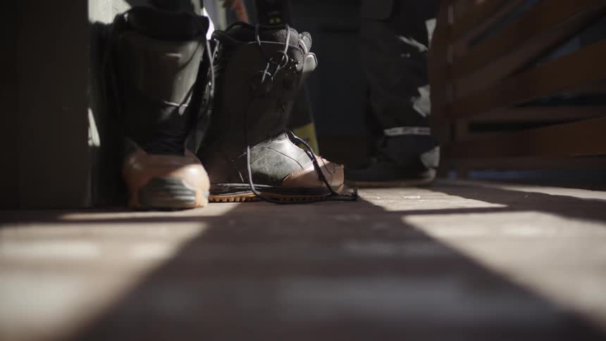 Two people leaving boots and equipment on the wall