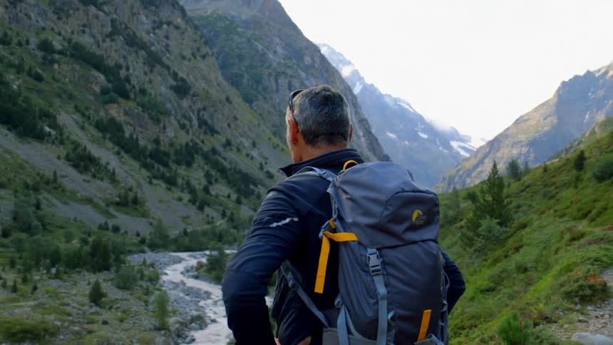 A hiker stands in front of a stream