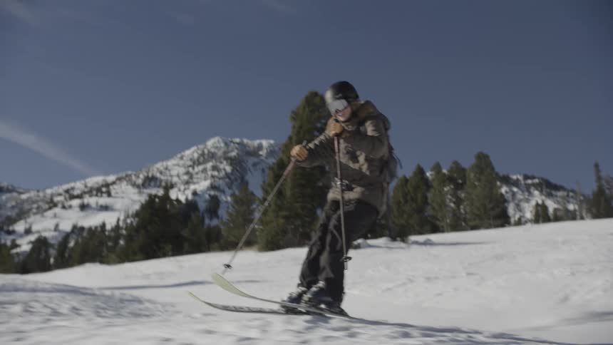 Skier holds their poles as they slide down a snow covered mountain slope