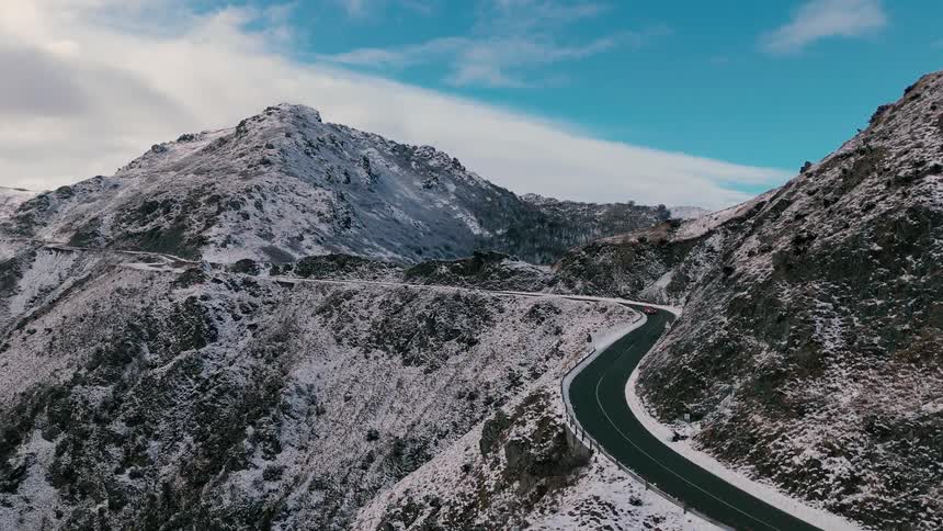 Car traveling on a road through snow covered forested mountains