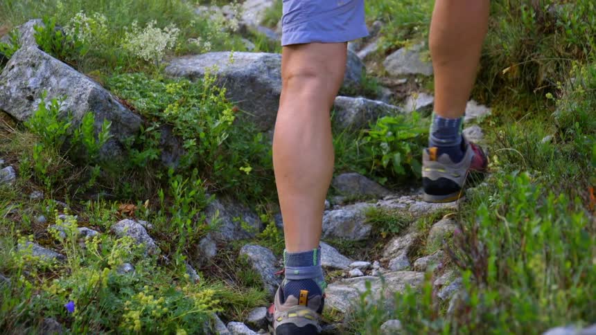 A person wearing shorts hikes up a rocky trail