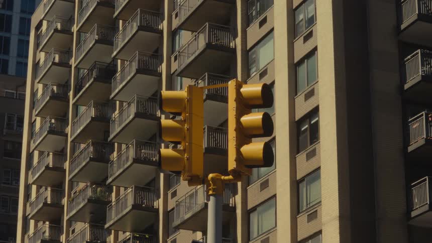 Yellow traffic light in front of a residential building with balconies