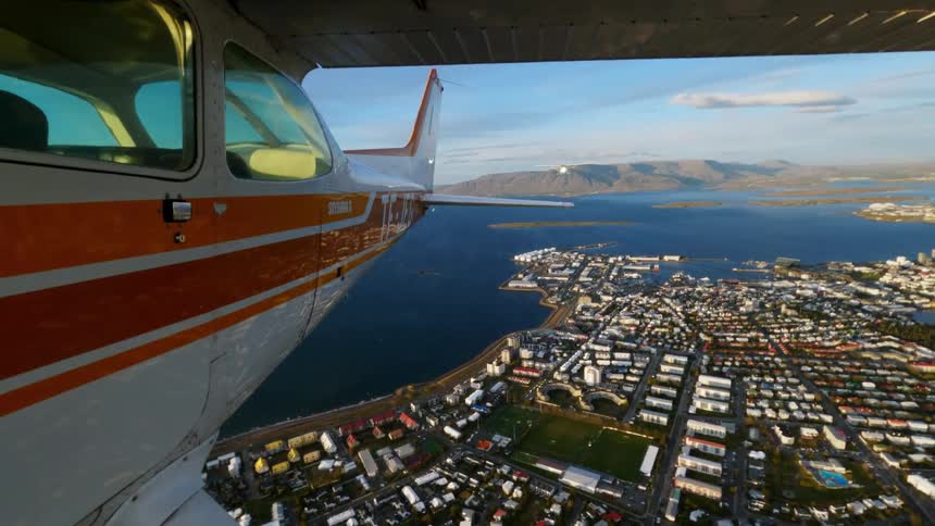 Singleengine airplane flies over a coastal city with lagoons and densely built neighborhoods