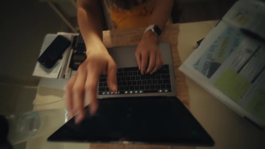 Teenage girl smiles as she types on the keyboard of a laptop computer and closes the lid