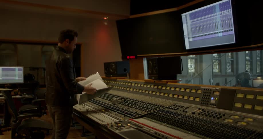 A man in a sound studio flips through a large book