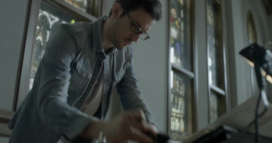 Man standing in a church looks down at papers