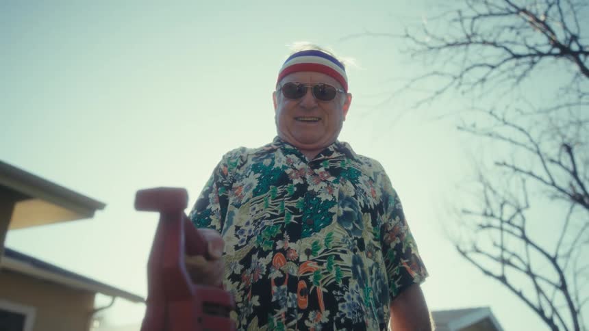 Elderly man standing in his front yard holding a leaf blower