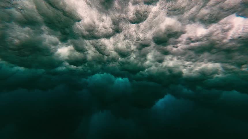 Foam and bubbles form beneath the surface of blue water