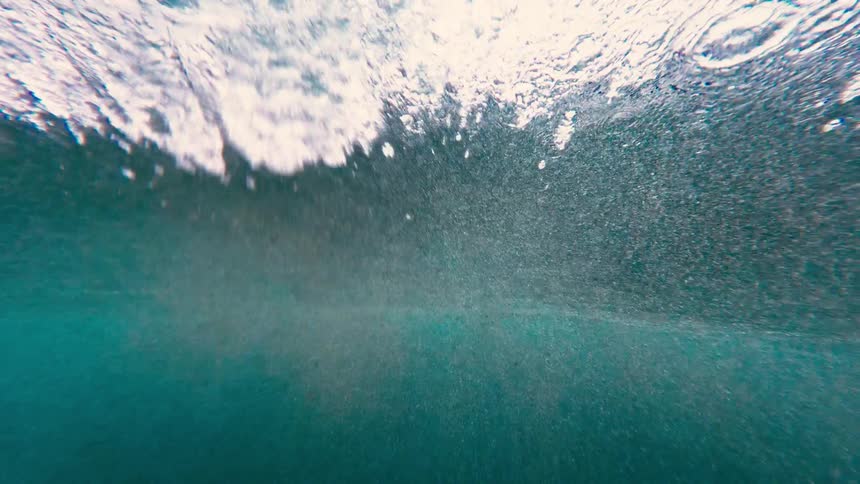 Bubbles and turbulence form beneath the surface of blue water