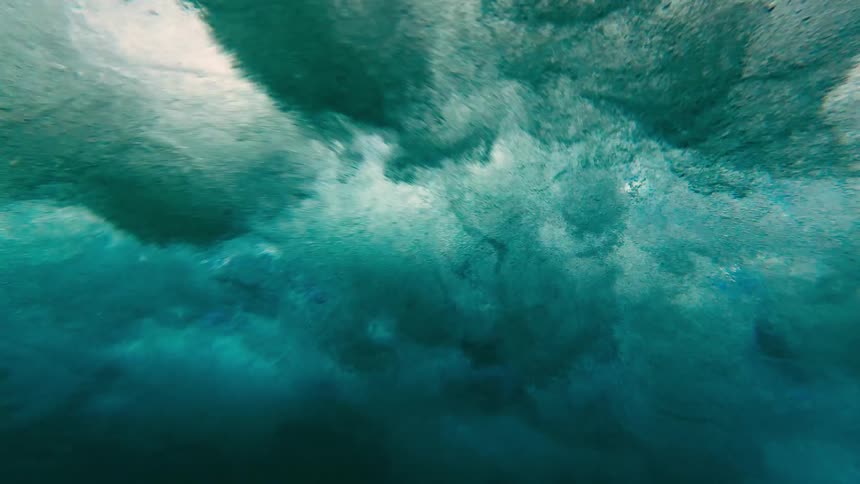 Waves create foam beneath the surface of blue water