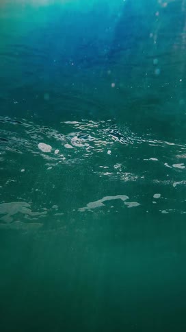 Rays of light penetrate the rippling surface of dark blue water