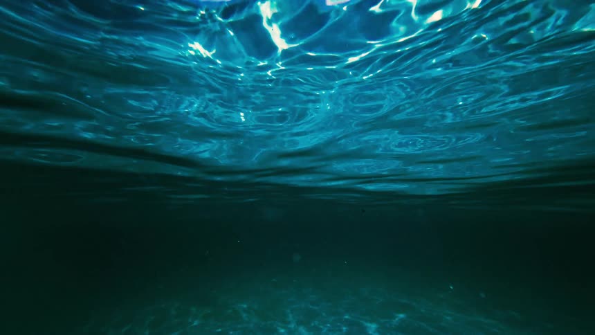 Undulating water surface seen from below in dark blue tone