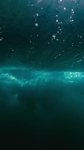 The wave crashes and moves underwater by the shore