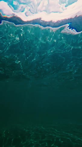 Bright sunbeams pierce through the surface of deep blue water creating shimmering light rays and lens flares in a clear ocean