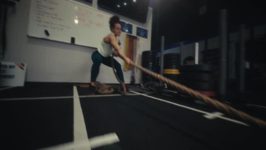 A determined female athlete pulls a heavy weighted sled toward her