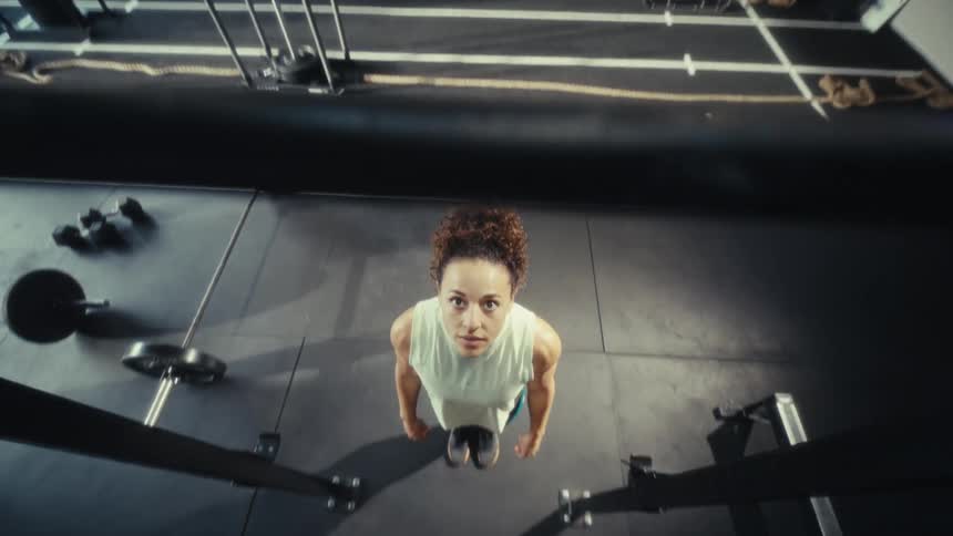 Woman standing in the gym looking at a pullup bar