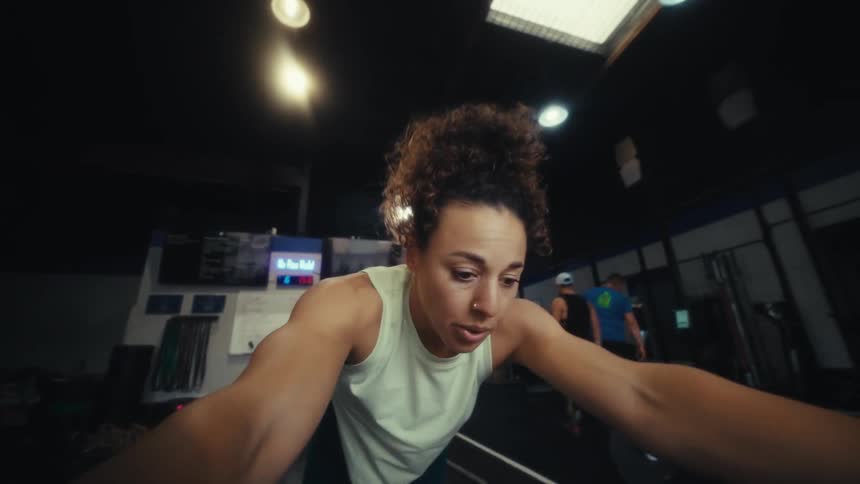 A woman exercises by pushing a weight sled across the gym floor