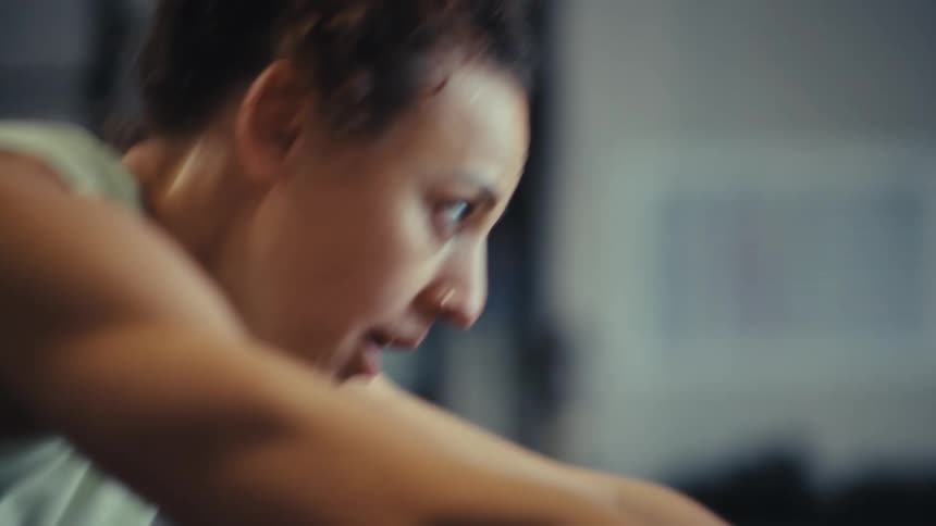 The woman is pushing equipment in the gym while she works out