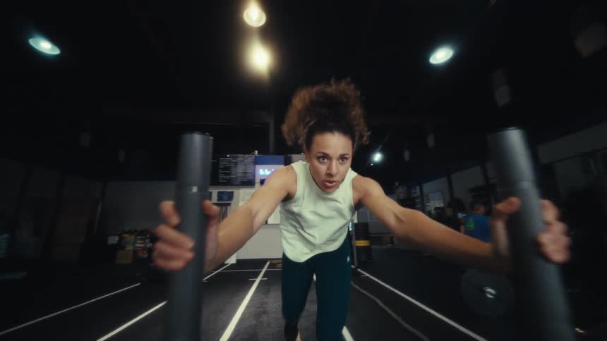 Young woman runs as she exercises pushing weights