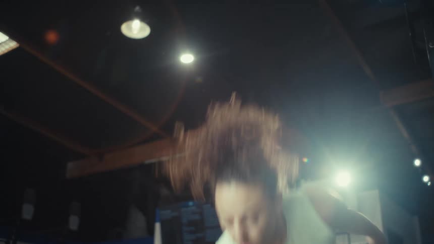 A woman in a gym performs a series of highintensity dumbbell snatches lifting the weight from the floor to high above her headthe scene uses a lowangle perspective and dramatic lighting to highlight her explosive movements and focus
