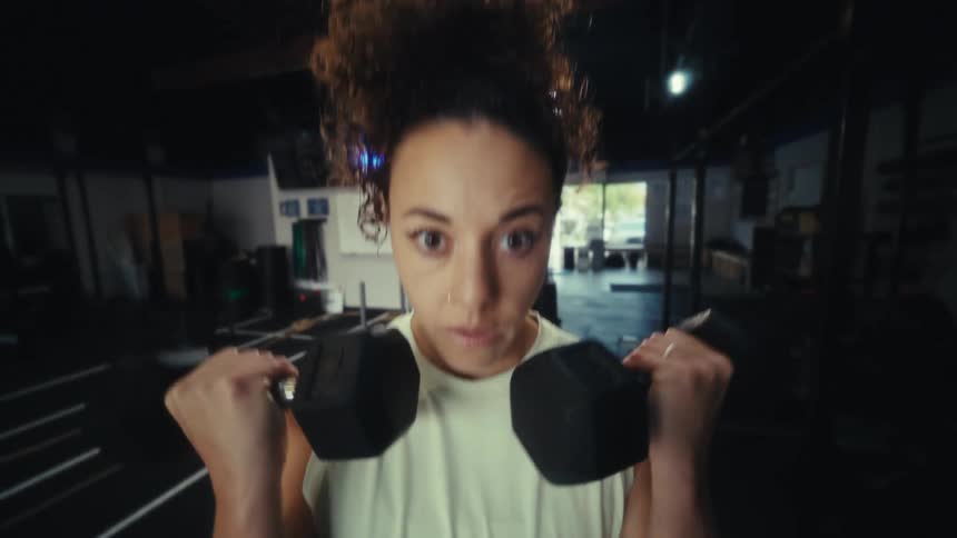 Young woman exercises lifting dumbbell weights with both hands