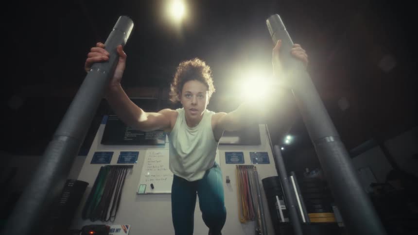 Young woman pulls a rope with weights then pushes the weights across the gym