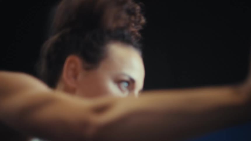The woman is pushing weights as she exercises in the gym