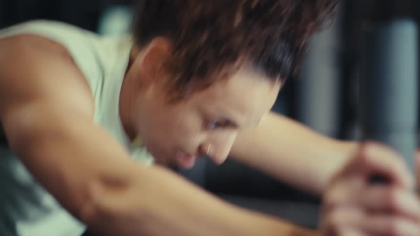 Woman leans forward during an intense workout in a gym